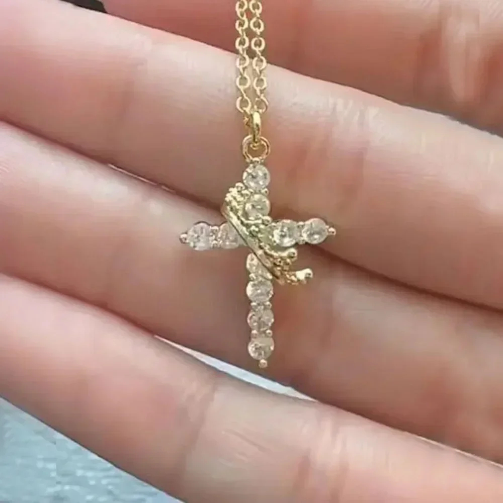 Delicate gold Y-shaped necklace featuring a crown and cross pendant, adorned with sparkling clear stones.