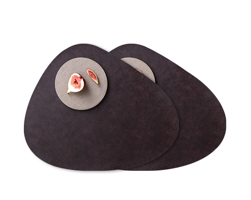 Two dark brown waterproof leather placemats showcased with a round plate holding a fig and a fig slice.