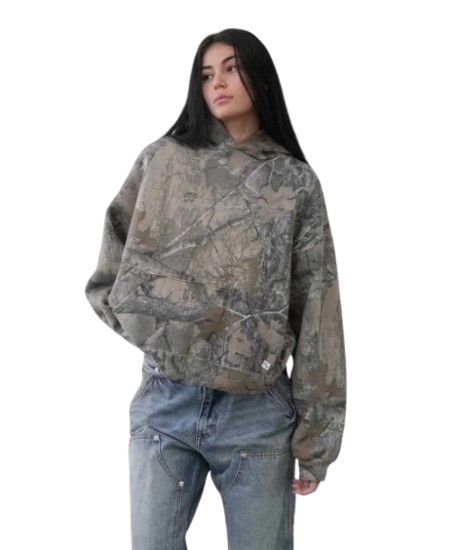 Unisex oversized hoodie in urban camouflage print, worn with relaxed fit jeans, featuring an adjustable hood and soft fabric.