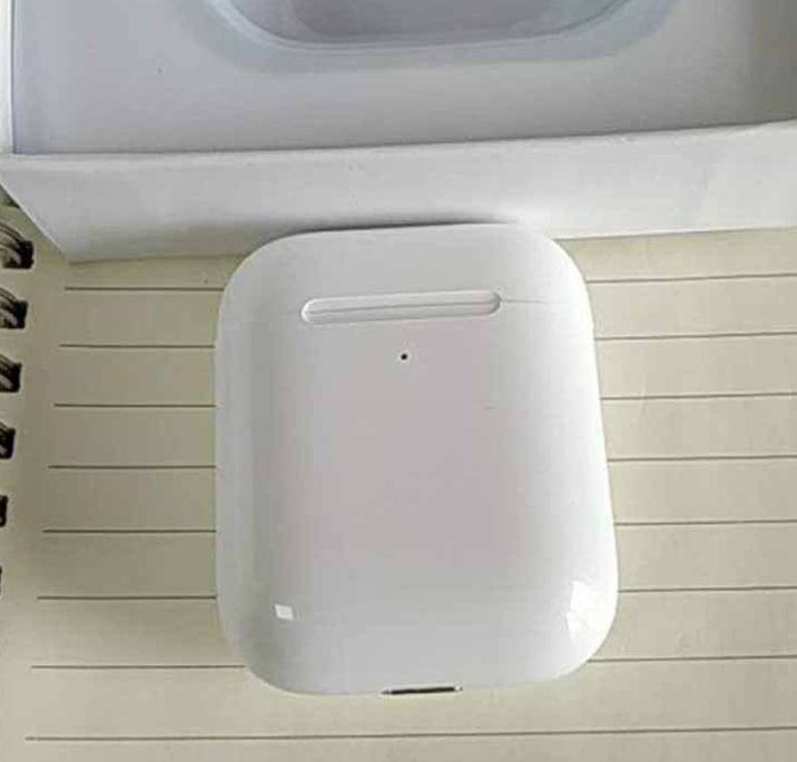 Compact white charging case for i80 TWS Bluetooth earbuds, resting on a lined notebook page.