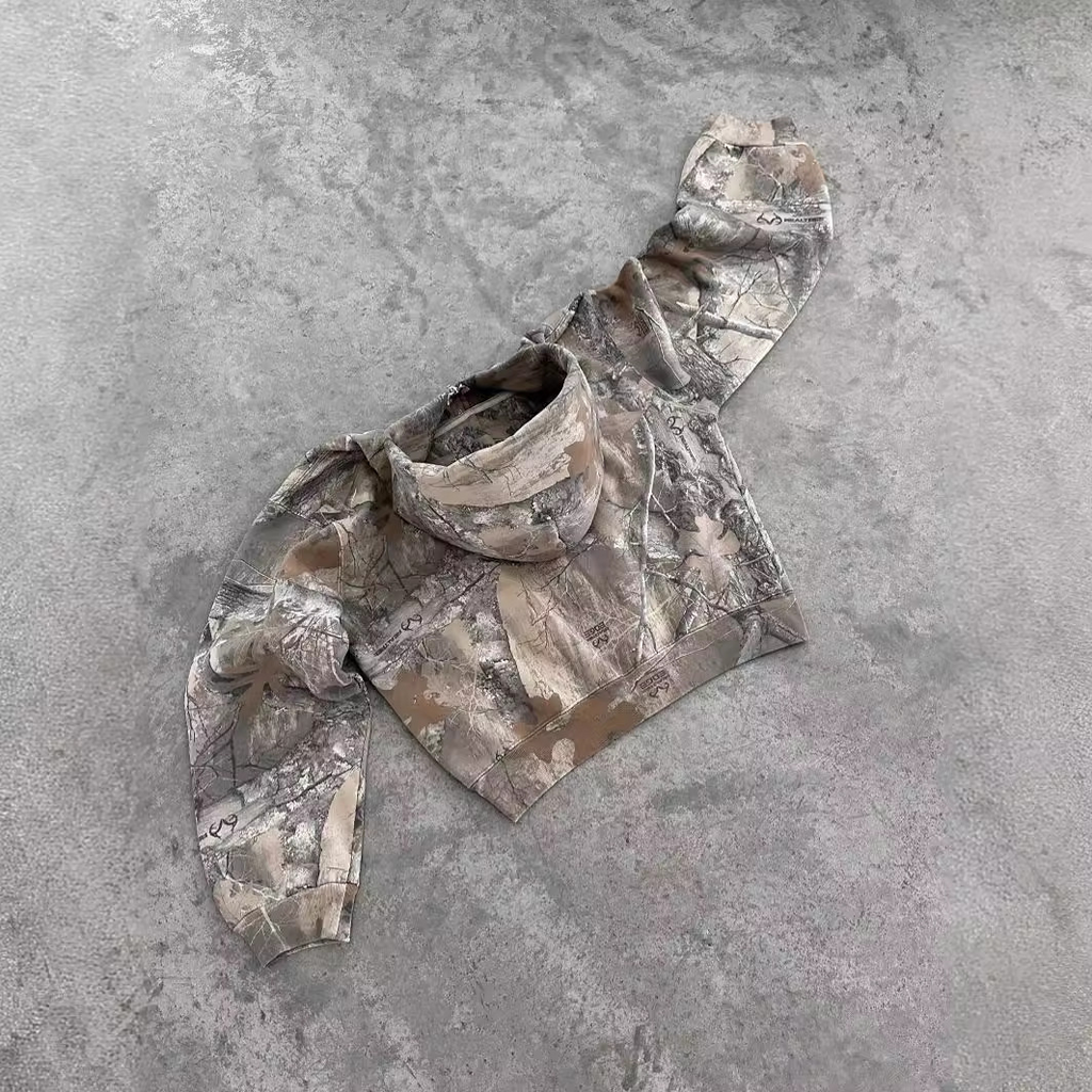 Oversized urban camo hoodie in shades of beige and gray, featuring a high collar, loose fit, and long sleeves.