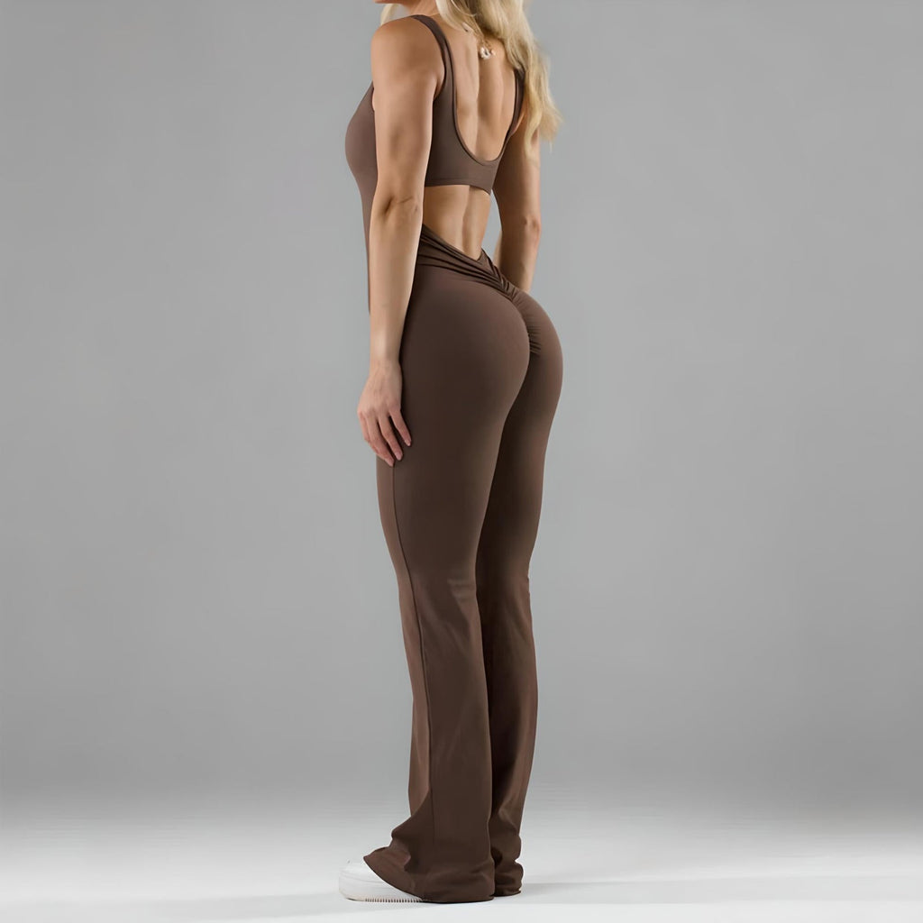 Brown flared jumpsuit with a fitted bodice, back cutout detail, and flared legs, styled with white sneakers.