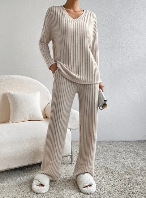 Casual 2-Piece Loungewear Set in ribbed beige fabric, featuring a V-neck top and relaxed pants paired with fluffy slippers.