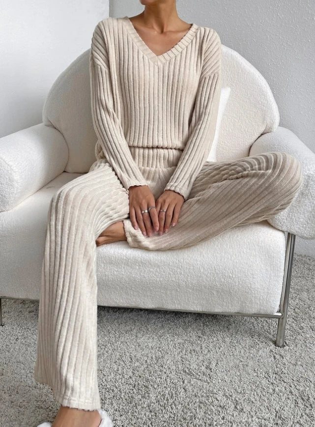 Beige ribbed 2-piece loungewear set featuring a V-neck long-sleeve top and relaxed fit pants, worn while sitting.