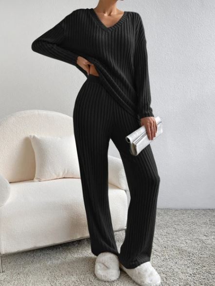Casual 2-Piece Loungewear Set in black, featuring a V-neck top and relaxed-fit pants with ribbed texture. Model holds a clutch.