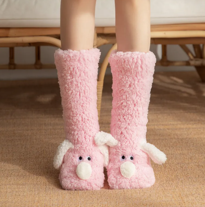 Soft pink plush dog socks with fluffy material, featuring a cute dog face and non-slip soles. Ideal for cozy wear at home.