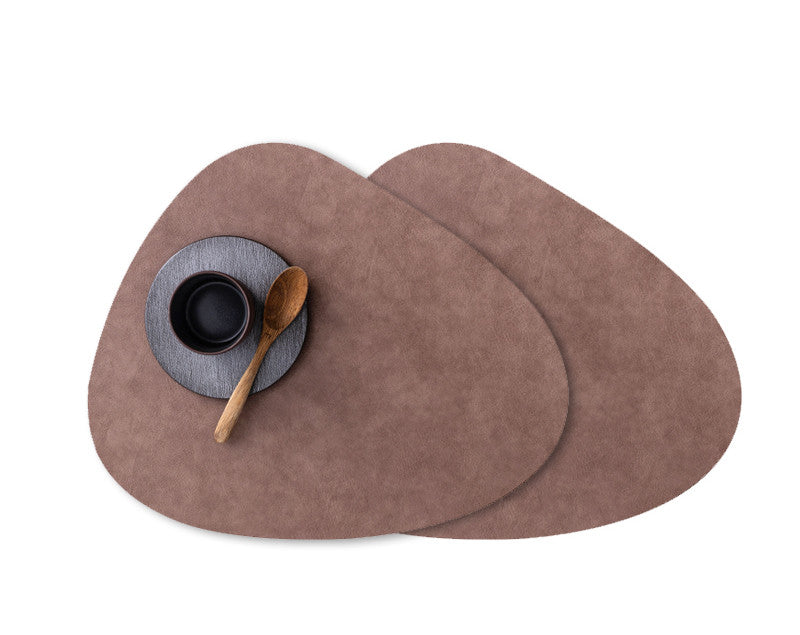 Brown waterproof leather placemats with rounded edges, topped with a black bowl and wooden spoon on a round gray mat.