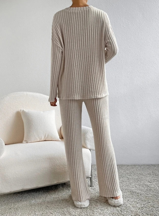 Cozy beige ribbed 2-piece loungewear set with a relaxed fit, featuring a long-sleeve top and matching pants, worn with slippers.