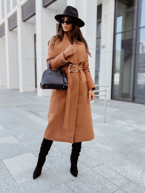 Long, camel woolen coat with a lapel collar, belted waist, and long sleeves, worn with black over-the-knee boots and a hat.