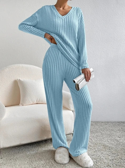 Light blue, ribbed 2-piece loungewear set featuring a V-neck top and matching wide-leg pants. Worn with fluffy slippers.